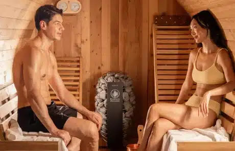 collections-hot-tub-wellness-redwood-3 Two adults sit on sauna benches facing each other in a wooden steam room, relaxing and talking.