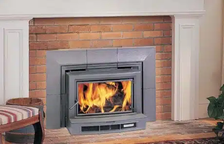 specials-fireplace-stove-2 Wood-burning stove glowing with flames set into a brick fireplace with a white mantel.
